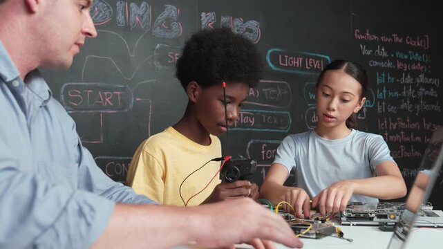 Young student fixing controller while teacher programming engineering code at STEM class. Closeup of instructor hand typing computer while smart girl using electronic tool and blackboard. Edification