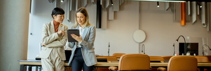 Business meeting between two colleagues in a modern office space with a tablet