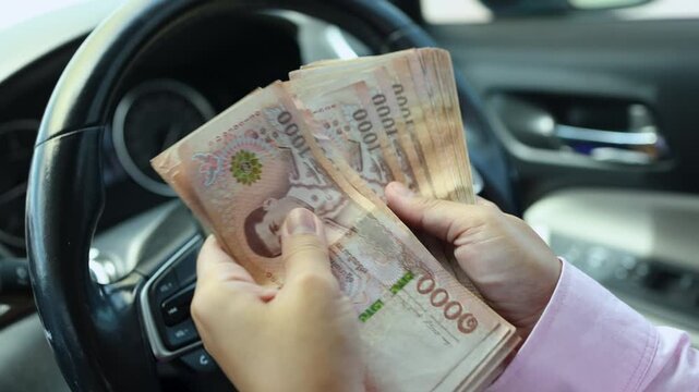 Hands counting money banknotes inside a car, Cash, Thai 1000 baht, symbolizing finance, wealth, business, spending, and luxury lifestyle