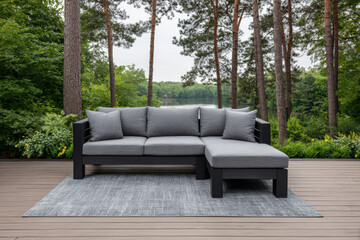 Fototapeta premium Modern outdoor sectional sofa set on deck by serene lake surrounded by tall trees in early morning light
