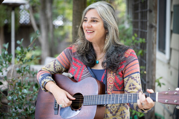 Woman playing acoustic guitar outdoors