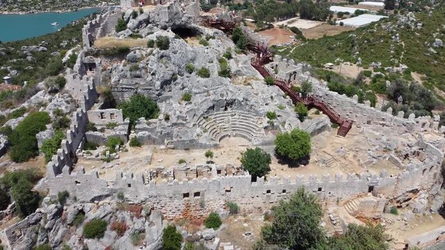 Drone video capturing the impressive hilltop ruins of an ancient amphitheater and fortress near Phaselis, Antalya Province. Rugged rocky landscape and coastal vistas enhance the historic setting.