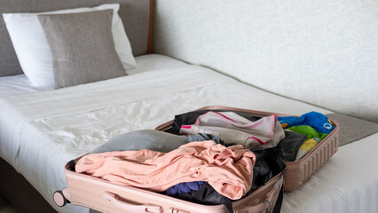 Open suitcase on hotel bed with travel items being prepared, capturing vacation planning moment