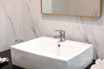 Modern washbasin with mirror and marble tiles, showcasing clean bathroom interior and elegant design