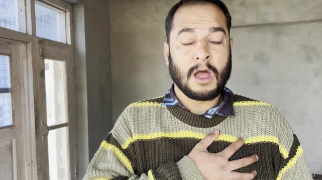 Infected person coughing very loudly holding his chest. Young man faces chest infection as he cough very badly. Chest disease concept, young patient cough holding his chest as he feels breathlessness.