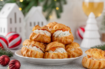 Savory profiteroles with smoked salmon, cream cheese and dill on a plate on a concrete background. Appetizer for Christmas and New Year. Selective focus, copy space.
