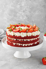 Naked Red velvet cake with fresh strawberries. Festive layered cake from red sponge cakes and cream cheese frosting. American cuisine.