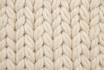 Close-up of thick cream-colored knitted wool texture.