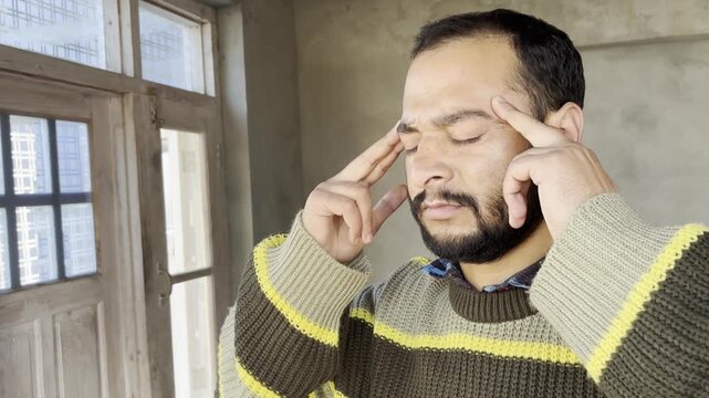 Calm silent man trying to focus on things as he massage on brain part to get cool and calm. Young guy trying to get rid of overthinking and anxiety. Young man doing mental exercise.