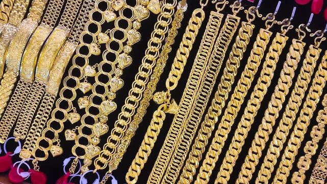 Gold jewelry, Rows of gold bracelet and necklaces displayed in jewelry store showcase, symbolizing wealth, investment, and luxury. Perfect for financial, economic, or gold market concepts