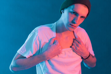 A portrait of a teenage boy looking at the camera and aggressively ripping his T-shirt off