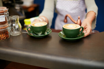 Cafeteria, coffee shop and hands of woman with drink at counter for service, help and hospitality. Restaurant, small business and person with caffeine, latte and beverage for serving customers