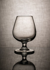 empty cognac glass with reflection on textured gray background