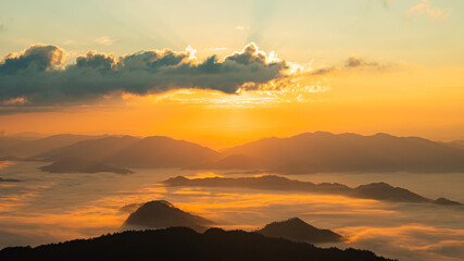 Serene Sunrise Over Mountain Range with Layers of Mist and Golden Light Illuminating the Sky and...