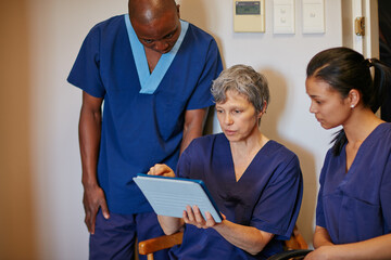 Conversation, meeting and tablet with medical team in hospital hallway for consulting or strategy. App, doctor and nurses with people in corridor of clinic for coaching, discussion or healthcare