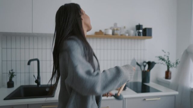 Portrait of funny african american woman dancing at home kitchen, good moods. Happiness and joy, young lady listening to music at weekend morning and enjoying rhythm, kitchenware for cooking in hands