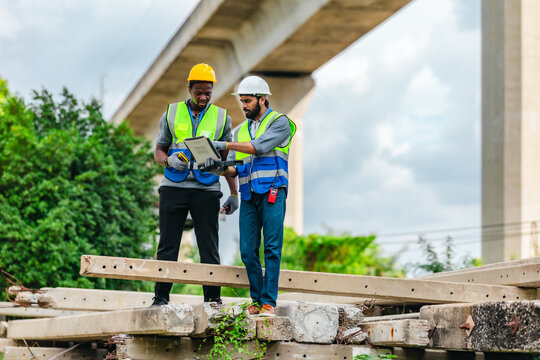 Railway engineer and technician inspecting concrete pier sections and construction debris