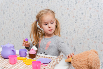 Little cute girl child organizes a tea party with toy dishes and Soft bear toys