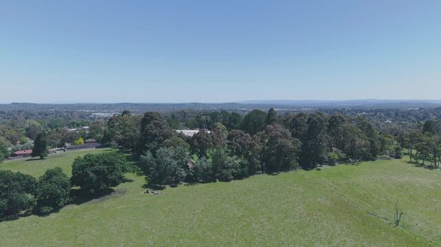 Drone footage captures a wide-angle view of lush greenery and forested landscape near Silvan Reservoir. The serene expanse under clear blue skies creates a tranquil and expansive natural scene.