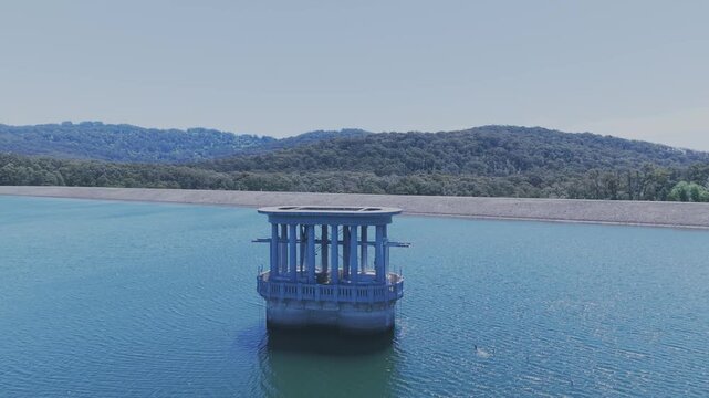 Breathtaking aerial footage of Silvan Reservoir&rsquo;s distinctive valve tower against serene waters and lush forestry. Captured with clarity, highlighting the tranquil, expansive landscape.
