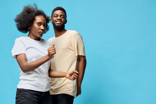 Young Black couple dancing playfully against a vibrant blue background, showcasing joy and connection, perfect for lifestyle and relationship themes - Powered by Adobe