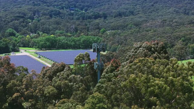 Drone video captures Silvan Reservoir's rich forest canopy with a telecom tower and solar panels. Vibrant green hues dominate this serene, untouched landscape. No people present.