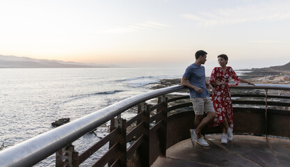 Horizontal photo of a couple talking at a viewpoint at sunset