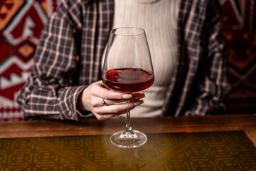 Woman holding glass of red wine at cozy table