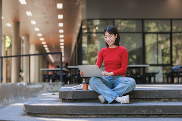 Young student working on laptop on campus steps