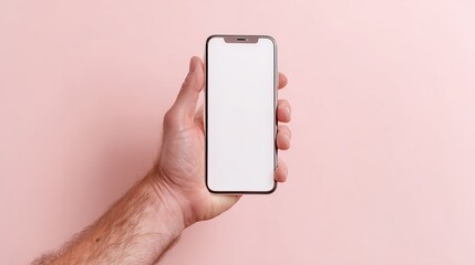 Person holds a blank smartphone in hand against a pink background for potential use