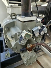 Close-up view of industrial compressor unit with multiple sensors and copper piping.