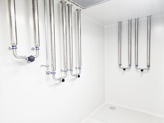 Cleanroom stainless steel piping system with valves and connections on a white wall.