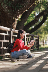 Obraz premium Young woman enjoying reading book in park