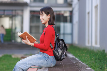 Young asian student woman reading book on campus