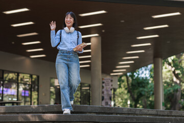 Young asian woman student waving walking downstairs on campus