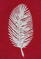 Close-up macro view of intricate white stitching forming a traditional feather design motif on a soft cotton textile for home decor ,abstract ,closeup ,pattern