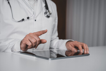 Male doctor using tablet device for digital healthcare teleconsultation in modern medical system concept on indoor background with futuristic touch.