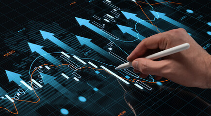 Hand with stylus touching futuristic digital screen showing growing financial charts and arrows on a high-tech business interface background.