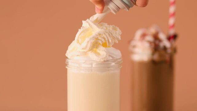 Adding Whipped Cream to Vanilla Milkshake with Dessert Background