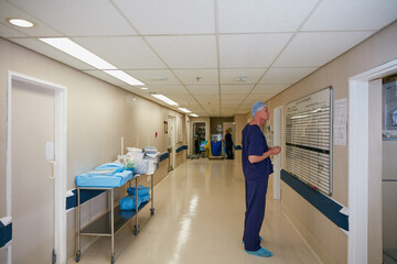 Surgeon, whiteboard or reading in hospital with schedule, operation theater roster or organization. Mature man, doctor and notice board in clinic with healthcare calendar, surgery timetable or space.