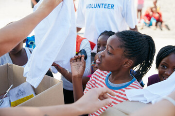Volunteer, outdoor and people with donation for children for outreach program, charity event and giving. Team, kids and group with boxes, clothes and parcels for community service, giveaway and aid