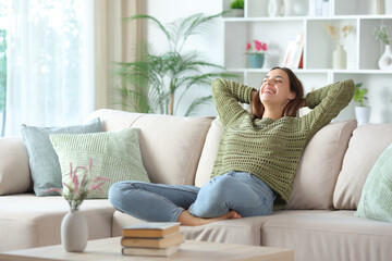 Obraz premium Happy woman in green relaxing on a couch at home