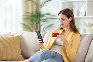 Woman in yellow buying online with card and phone on a couch