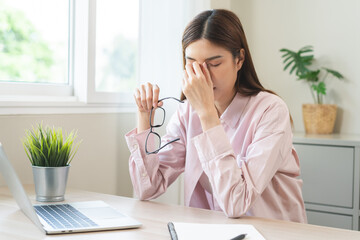 Eye problem concept, fatigue asian young woman tired eyes, irritated rubbing nose, relief vision pain after work on laptop computer, eye strain, hand holding glasses, suffer migraine, bad blurry.