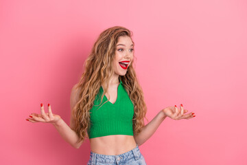 Young woman in green top making expressive gestures against a pink background in casual and stylish...