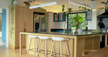 Camera starting recording wooden kitchen island with black top, white stools showing modern layout