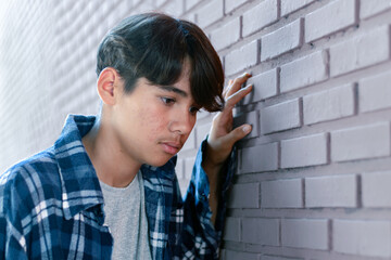 A quiet moment of reflection as the boy stands by the wall, lost in his own thoughts.