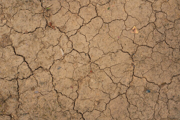 The surface of the earth was cracked by drought, cracks and erosion in the soil. Brown dry soil or cracked ground texture background. clay soil texture after water dry out and arid.