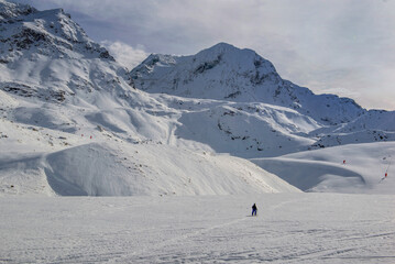 beautiful white snowy peak mountain in alpine ski resort under white cloud in the sky and a touring skier far away