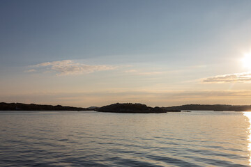 Obraz premium Beautiful summer evening with a spectacular sunset over the Gothenburg Archipelago and the calm water of the North Sea seen from the rocky coastline of the small island Vrango with a swimming jetty